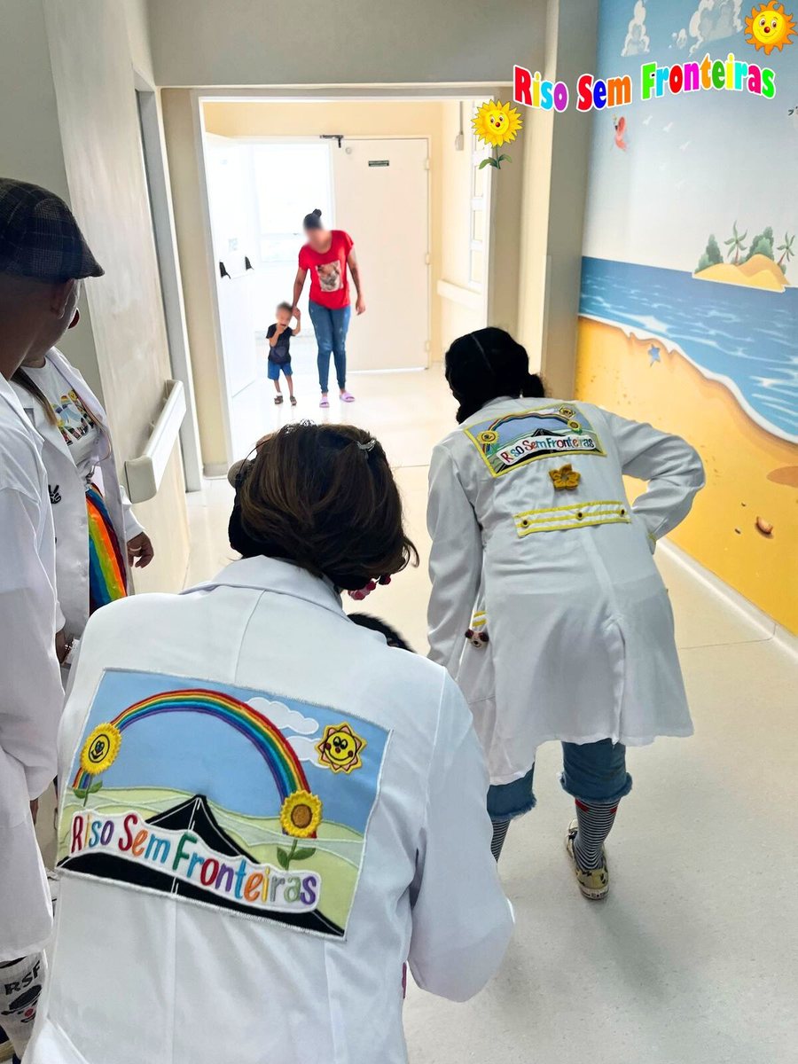 Voluntárias caminhando no corredor do hospital infantil com jalecos da Riso Sem Fronteiras
